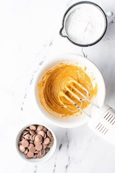 a bowl with peanut butter and a whisk in it next to other ingredients