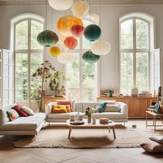 a living room filled with lots of furniture and large round lamps hanging from the ceiling