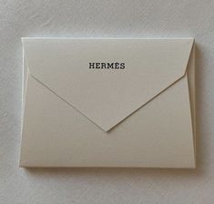 an envelope with the word hermes written in black ink on it, sitting on a white surface