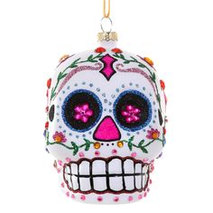 a glass ornament shaped like a skull with pink eyes and flowers on it