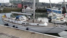 a sailboat docked at a dock with other boats in the water