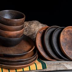 a stack of wooden bowls sitting on top of a table next to a piece of wood