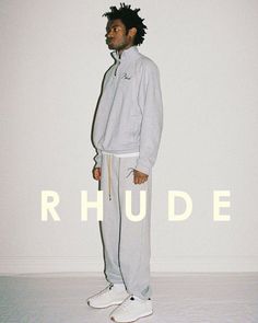 a man standing in front of a white wall with the words rhude on it