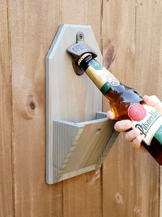 a person opening a bottle opener on a wooden fence with a beer in it's hand