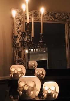 there are candles that have been placed on the table with skulls in front of them