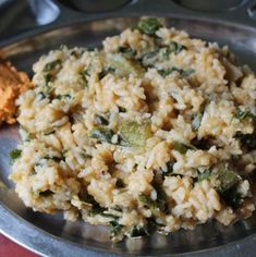 a plate full of rice and vegetables on a red tablecloth with other food items