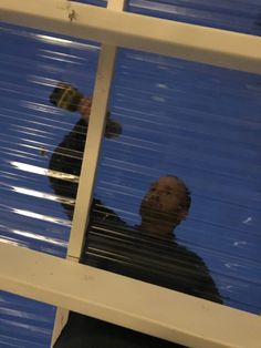 a reflection of a man holding a beer in his hand and looking out the window