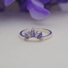 three stone ring sitting next to purple flowers