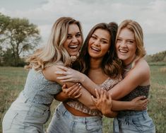 three women hugging each other in a field