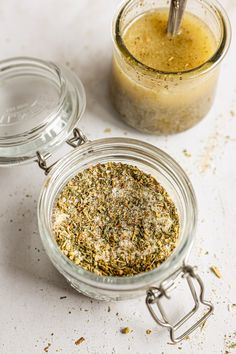 two glass jars filled with different types of spices and seasoning next to each other