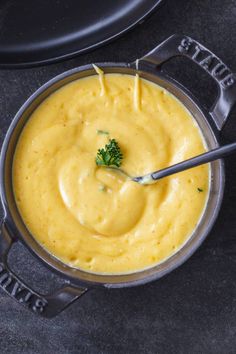 a pot filled with yellow sauce and broccoli garnished with parsley