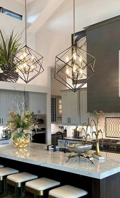 a kitchen island with stools and lights hanging from it's ceiling above it