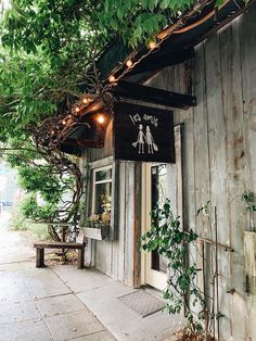 an old wooden building with a sign on the front door and trees growing out of it