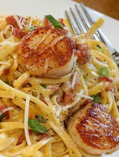 some scallops are on top of pasta and garnished with parmesan cheese