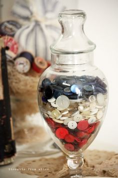 a glass jar filled with buttons on top of a table