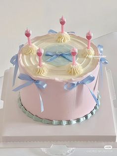 a pink cake with blue bows and candles