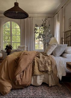 a large bed in a bedroom next to a window with lots of curtains on it