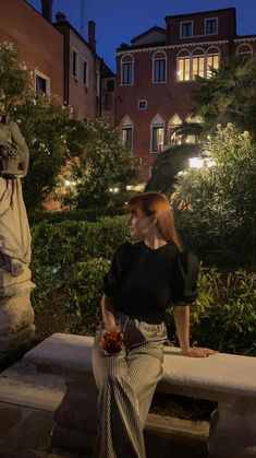 a woman is sitting on a bench in the evening