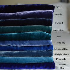 a stack of blue and green pillows on top of a white bed with the names of each pillow