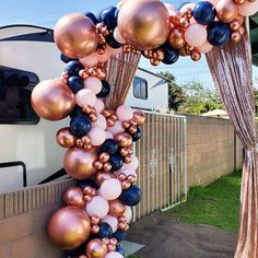 an arch made out of balloons in front of a house with a motor home behind it