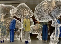 mannequins dressed in blue and yellow with umbrellas on display behind them