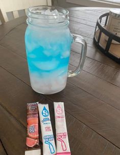 a glass jar filled with blue liquid next to three bars of chocolate on top of a wooden table