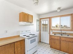 an empty kitchen with white appliances and wooden cabinets