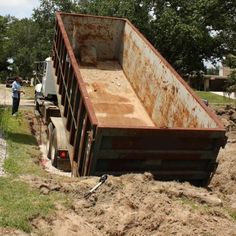 an old dump truck is parked in the dirt