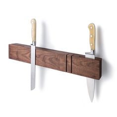 two knives are hanging on the wall next to a knife holder with three knives in it