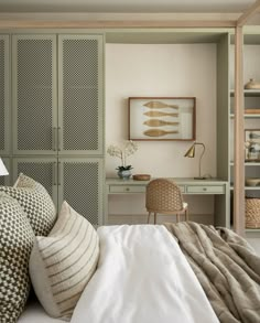 a bedroom with green cabinets and white bedding