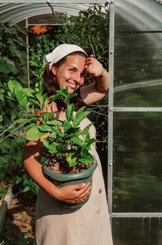 a woman is holding a potted plant in her hands and posing for the camera