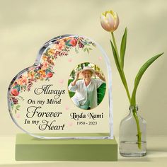 a heart shaped glass vase with a flower in it and an image of a woman's face