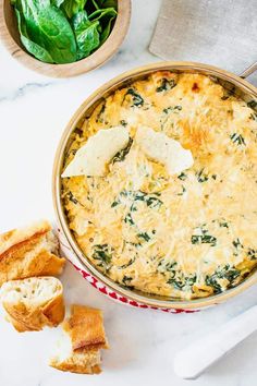 a casserole with spinach and cheese in a red dish next to bread