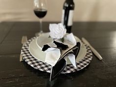 a black and white checkered plate with two wine glasses on it next to an origami flower