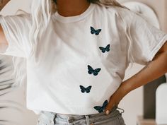 a woman with white hair and blue butterflies on her t - shirt is taking a selfie