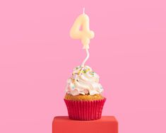 a cupcake with white frosting and sprinkles is on top of a red block