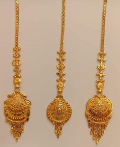 three gold necklaces with designs on them