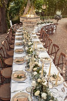 a long table is set with plates and place settings for an elegant dinner in the garden