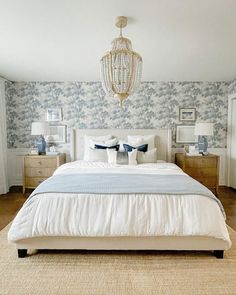 a large bed sitting in a bedroom next to two nightstands and a chandelier