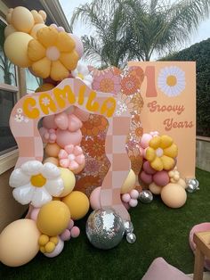 balloons and flowers are on display in front of a sign for a baby's first birthday