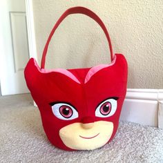 a red bag with a face on it sitting in front of a white wall and door