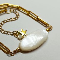 Discover our AVA natural mother-of-pearl bracelet with a star pendant gilded with 24K fine gold! This jewel combines the timeless elegance of mother-of-pearl pearls with the refined shine of the star pendant gilded with fine 24K gold. The delicacy of the mother-of-pearl bead and the shine of the pendant create a perfect harmony, adding a touch of luxury to your wrist. Carefully crafted, this natural mother-of-pearl AVA Bracelet is ideal for everyday use or for special occasions. Its careful desi Gold Bracelet With Pearl Pendant For Gift, Gold Bracelet With Pearl Pendant As Gift, Pearl Charm Mother Of Pearl Bracelets As Gift, Gold Star Pendant, Bridesmaid Gifts Jewelry, Jewelry Bridesmaid, Perfect Harmony, Star Pendant, Bridesmaids Gifts