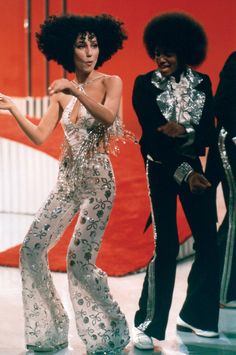 two women in disco outfits standing next to each other