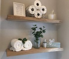 two shelves with towels, candles and other items on them in a home bathroom area