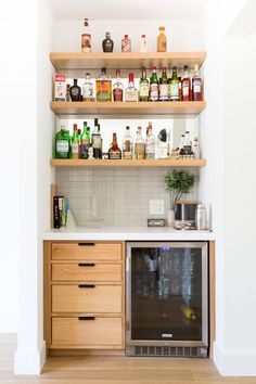 At-home bar niche features three wood shelves and wood lower cabinets next to mini refrigerator. Shelves have various spirit and alcohol bottles displayed. Tile backsplash with ribbed design. Small Bars For Home, Kitchen Bar Design, Home Wet Bar, Closet Bar, Home Bar Rooms, Modern Home Bar, Home Bar Design, Diy Home Bar