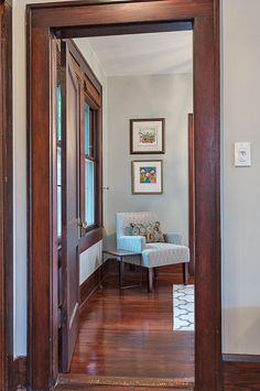 an open door leading to a living room with a chair and pictures on the wall