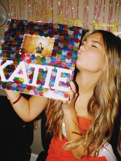 a woman holding up a box with the word kate on it in front of her face