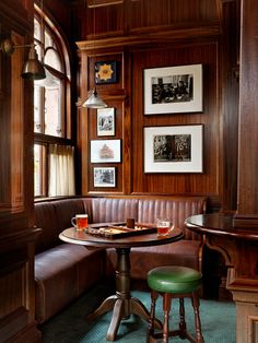 there is a table and two stools in the corner with pictures on the wall