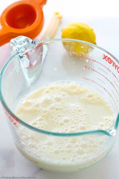 a glass measuring cup filled with liquid next to an orange slice