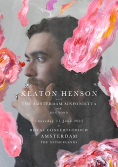 a man with long hair and beard standing in front of a poster that says keaton henson